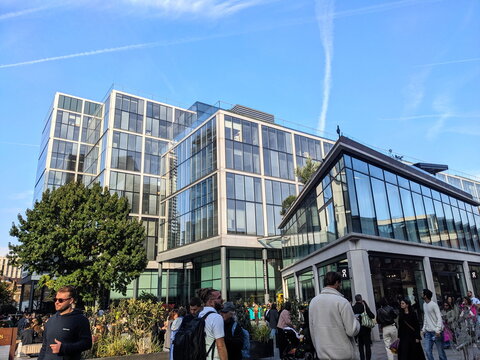 A vibrant crowd explores the modern architecture of London's famous Spitalfields Market on a sunny day