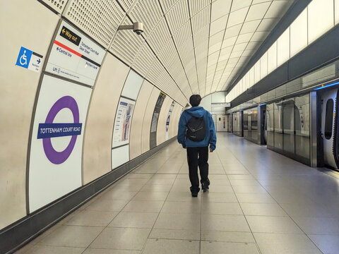 Lone commuter walking along the Elizabeth Line platform of Tottenham Court Road tube station, London