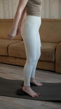 Woman doing balance practice during home fitness session. Indoor leg and core workout, strengthening lower body muscles, shaping toned figure, squats for firm buttocks, wellness lifestyle idea.