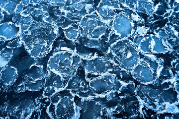 A close-up of cracked ice chunks on a river's surface, creating stunning natural texture. Perfect winter frost background with intricate patterns and sharp fragments.