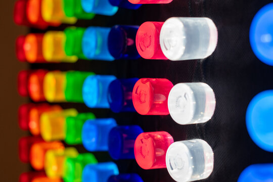A black light box with a black background and rows of colorful lite pegs. The rows of pegs include blue, white, red, green, yellow, orange, and red. The pegs are round plastic tubes.