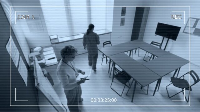 Security camera footage of mature female teacher arranging classroom and welcoming inmates for lesson during prison education program, copy space