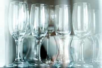Glasses behind a glass display case, showcasing elegant transparent glassware arranged neatly on shelves.