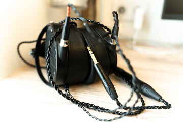 Black monitor headphones on table with audiophile wires, representing high-quality music listening. Professional audio equipment for studio monitoring, critical listening
