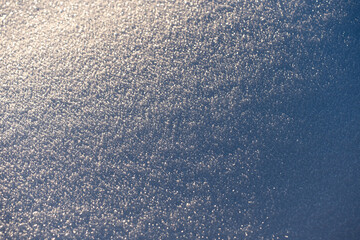 Texture of snow in warm sunlight, creating beautiful frozen nature background. soft winter light highlights delicate crystalline structure. winter themes, natural abstract concepts.