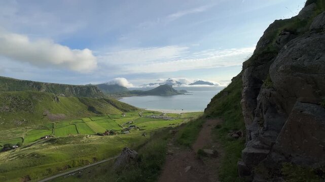 Cinematic panoramic footage of the stunning Haukland Beach coastline with turquoise sea, white sand, and dramatic mountain peaks in Lofoten, Norway