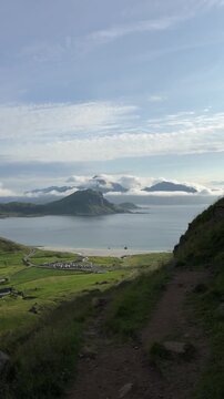 Cinematic panoramic footage of the stunning Haukland Beach coastline with turquoise sea, white sand, and dramatic mountain peaks in Lofoten, Norway