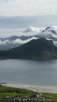 Cinematic panoramic footage of the stunning Haukland Beach coastline with turquoise sea, white sand, and dramatic mountain peaks in Lofoten, Norway