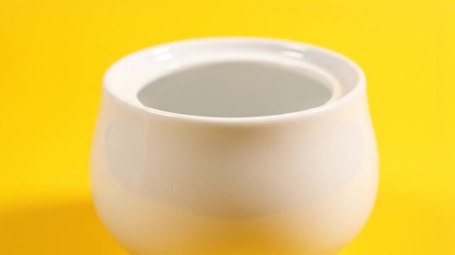 Empty White Sugar Bowl on a Vibrant Yellow Background.