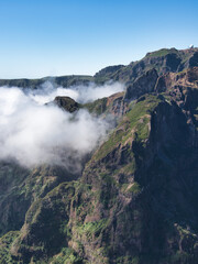 Dramatic Madeiran Mountain Peaks and Clouds - Vertical view of rugged volcanic peaks covered in green vegetation, with low clouds rolling through the deep valleys.