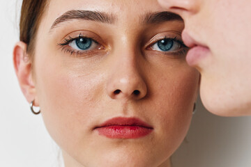 Fototapeta premium Close up portrait of young woman with blue eyes and red lips looking at camera with serious expression against white background. Beauty, skin, face details.