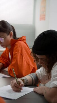 Vertical shot group of young women as female inmates studying and doing tasks attending class in prison education program