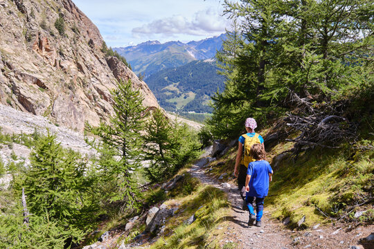 Rear view of a mother with her child walking along a mountain path