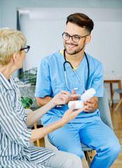 Obraz premium Doctor or nurse caregiver showing a prescrption drug bottle to senior woman at home or nursing home