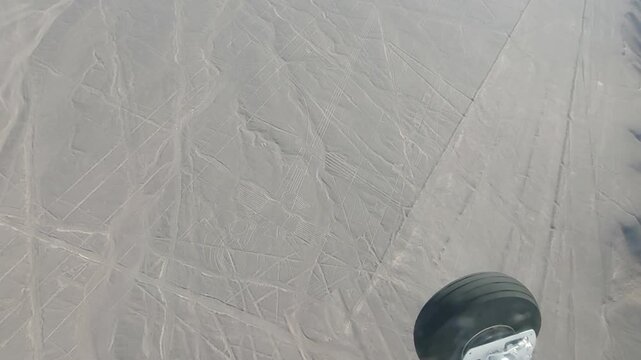 Nazca, Peru - 5 December 2025. View from a light aircraft of the Hummingbird geoglyph carved into the desert surface, with a plane wheel visible at the edge of the frame.