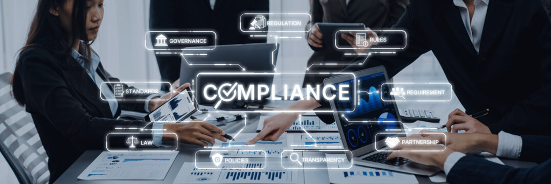 Group of business professionals working together on compliance strategies, featuring documents and technology to enhance governance and risk management efforts. Trope