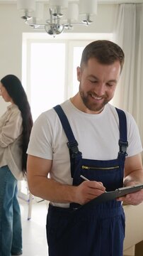 Professional mover writing on clipboard and smiling