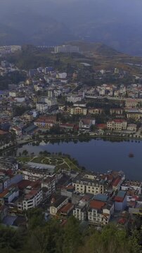Aerial view of Sapa, Vietnam, showcasing the town's architecture and scenic lake. Tourists visit to experience the culture and landscape of the region.
