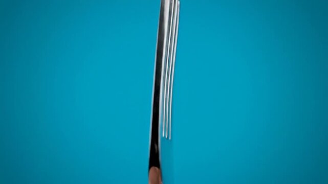 Close-up of a Shiny Silver Fork Against a Vibrant Blue Background.