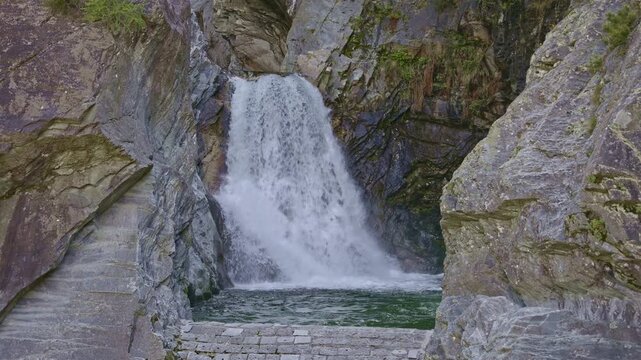 A scenic waterfall tumbling through a steep, wooded gorge. Cascata della Boggia waterfall, Lombardy, Italy.