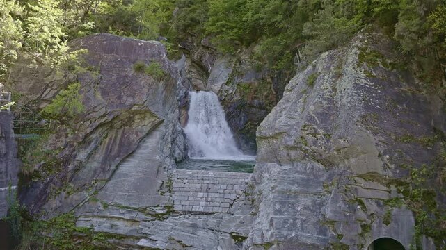 A scenic waterfall tumbling through a steep, wooded gorge. Cascata della Boggia waterfall, Lombardy, Italy.