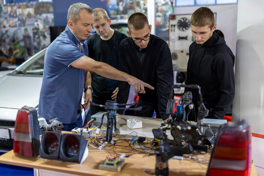Teacher educating young students in automotive electronics class