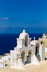 Fototapeta premium Santorini's iconic white bell tower against the blue Aegean.