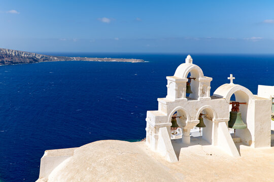 Santorini bell tower with caldera view and deep blue sea.