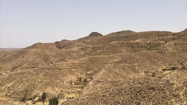 Terraced agriculture desert hills with sparse greenery in a semi-arid landscape near Matmata, Tunisia