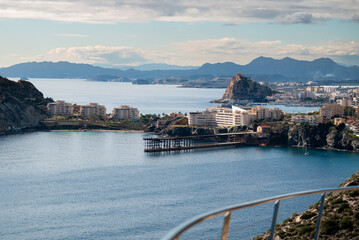 Aguilas, murcia, spain, showing the mediterranean sea coastline with the historic embarcadero del hornillo iron pier and modern buildings under a cloudy sky