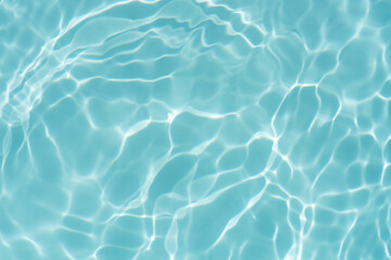Obraz premium Blue water with ripples on the surface. Defocus blurred transparent blue colored clear calm water surface texture with splashes and bubbles. Water waves with shining pattern texture background.