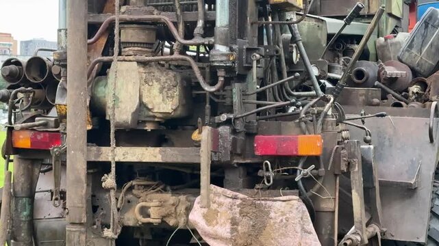 Drilling rig extracting soil cores in grassy field, truck mounted rotary rig creating borehole while driller operates controls, core tray with cylindrical samples laid on grass, geologist.