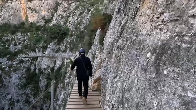 Seguimiento trasero de hombre caminando por la pasarela de Relleu