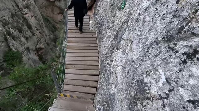 Hombre descendiendo escalones de madera en pasarela de Relleu