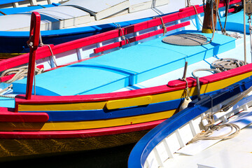 Colorful boat docked at a marina with reflections in water, summer scene, vibrant colors, outdoor setting, sunlight highlights, stationary vessel.