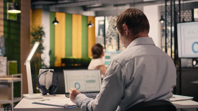 Professional worker reviewing compliance data on laptop screen at desk, ensuring performance review and doing risk assessment in office. Visual data for business intel support productivity.
