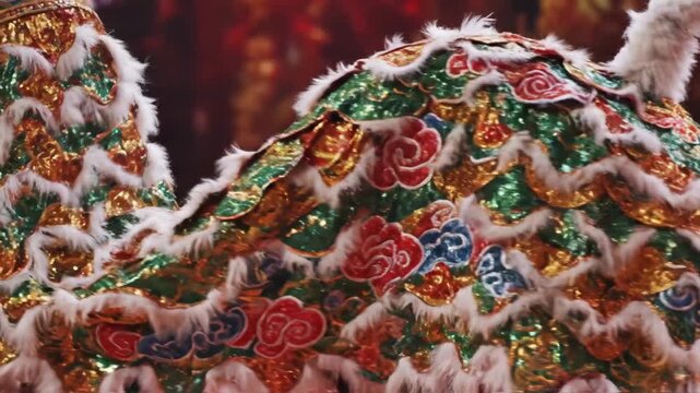 Chinese lion dance performance for Lunar New Year. Traditional costume with gold and red sequins dancing during a festival. Cultural celebration with red lanterns background