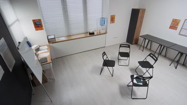 Wide angle shot of chairs set in circle for support group in empty meeting room at correctional facility, copy space