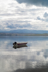 With calm, reflective sea and boats and cloudy sky
