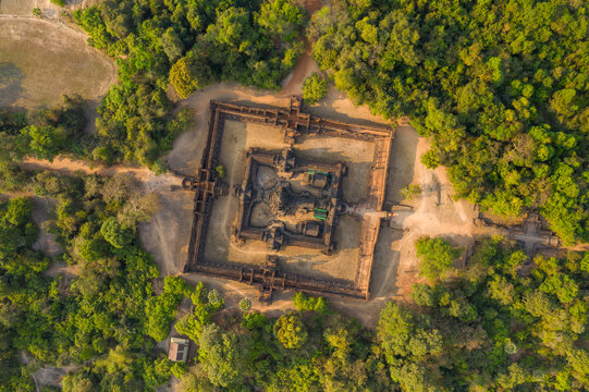 Symmetrical bird's-eye perspective of Banteay Samre temple surrounded by dense tropical forest in the Angkor region. The ancient sandstone complex stands out amid rural clearings under warm daylight