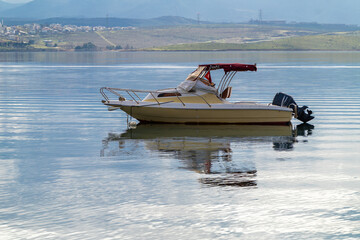 With calm, reflective sea and boats and cloudy sky