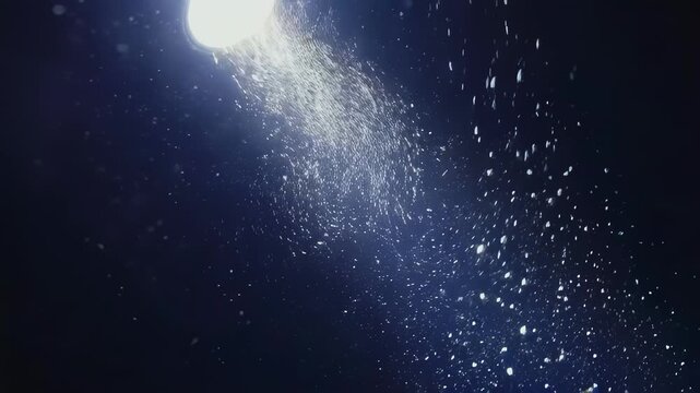 Light source illuminates particles suspended in dark space, showcasing a gradual increase in visibility and density of the particles in a continuous flow