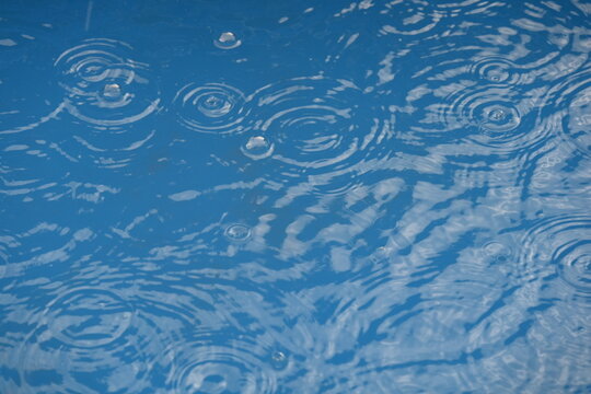 close up of blue water in swimming pool with rain drops