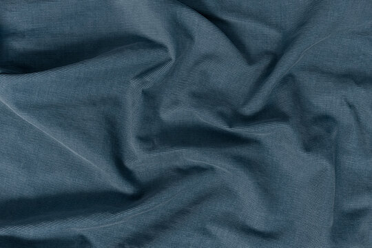 Detailed texture of a corduroy fabric background. Top view of a rich blue, navy, denim, slate tone textile material softly draped to create an abstract background