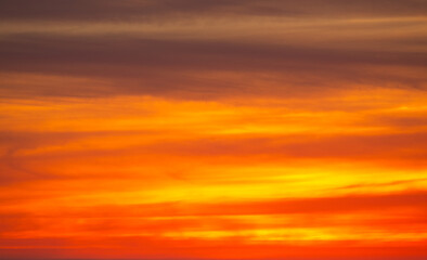 Fototapeta premium Orange and pink sunset sky with soft glowing clouds. Warm golden gradient background with smooth pastel tones and tranquil evening atmosphere. Natural abstract sky texture