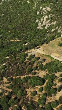 Scenic aerial shot of a rugged Mediterranean hillside covered with green trees and rocky terrain near Pigna. Natural landscape ideal for travel and nature concepts.