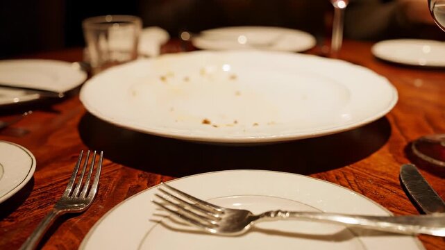 Empty dinner plates on wooden table after meal.