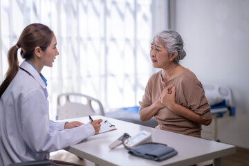 Fototapeta premium Senior woman having chest pain during doctor consultation
