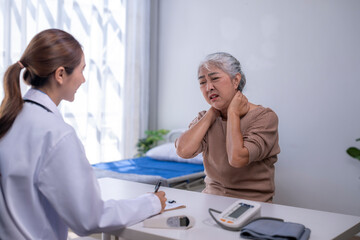 Obraz premium Senior woman describing neck pain to doctor at clinic