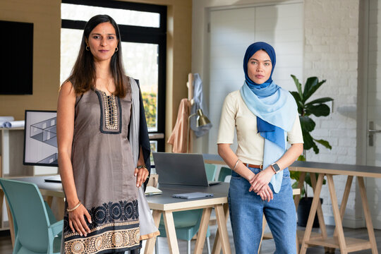 Asian Indian women standing in modern office workspace holding laptop and reviewing 3D design
